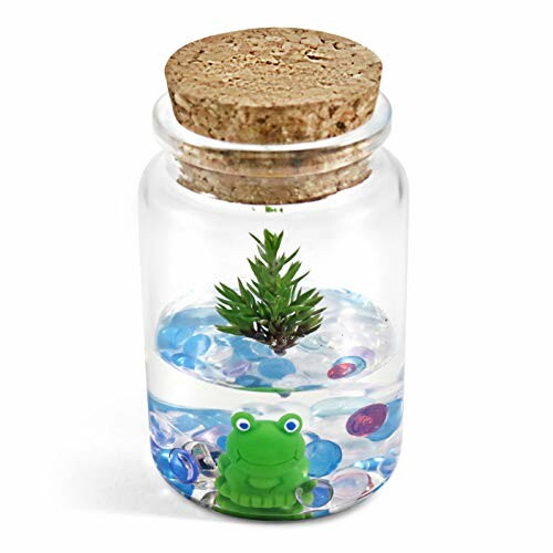 Decorative glass jar with cork lid, featuring a small green frog, blue pebbles, and a tiny plant inside.